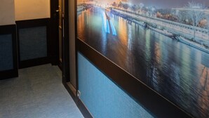 A hallway with a large poster of the Eiffel Tower at night, a door, and a wall-mounted light fixture. - Hotel Amiral Fondary (Paris)