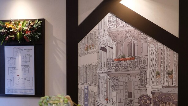 A reception area with a black and white patterned wall, a reception desk with a plant, and a monitor displaying a hotel layout. - Hotel Amiral Fondary (Paris)