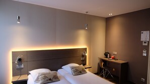 A modern hotel room with a large bed, bedside tables, a desk, and a chair. - Hotel Amiral Fondary (Paris)
