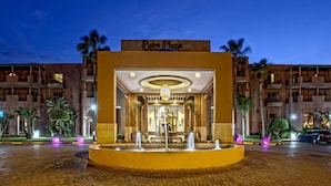 Entrada de hotel con una fuente, palmeras y un letrero que dice 'Palm Plaza'.