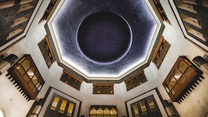 Una sala amplia y octogonal con una claraboya circular en el centro y varios balcones con barandillas de madera ornamentadas.