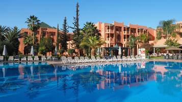 Alberca techada, alberca al aire libre y sombrillas en la alberca