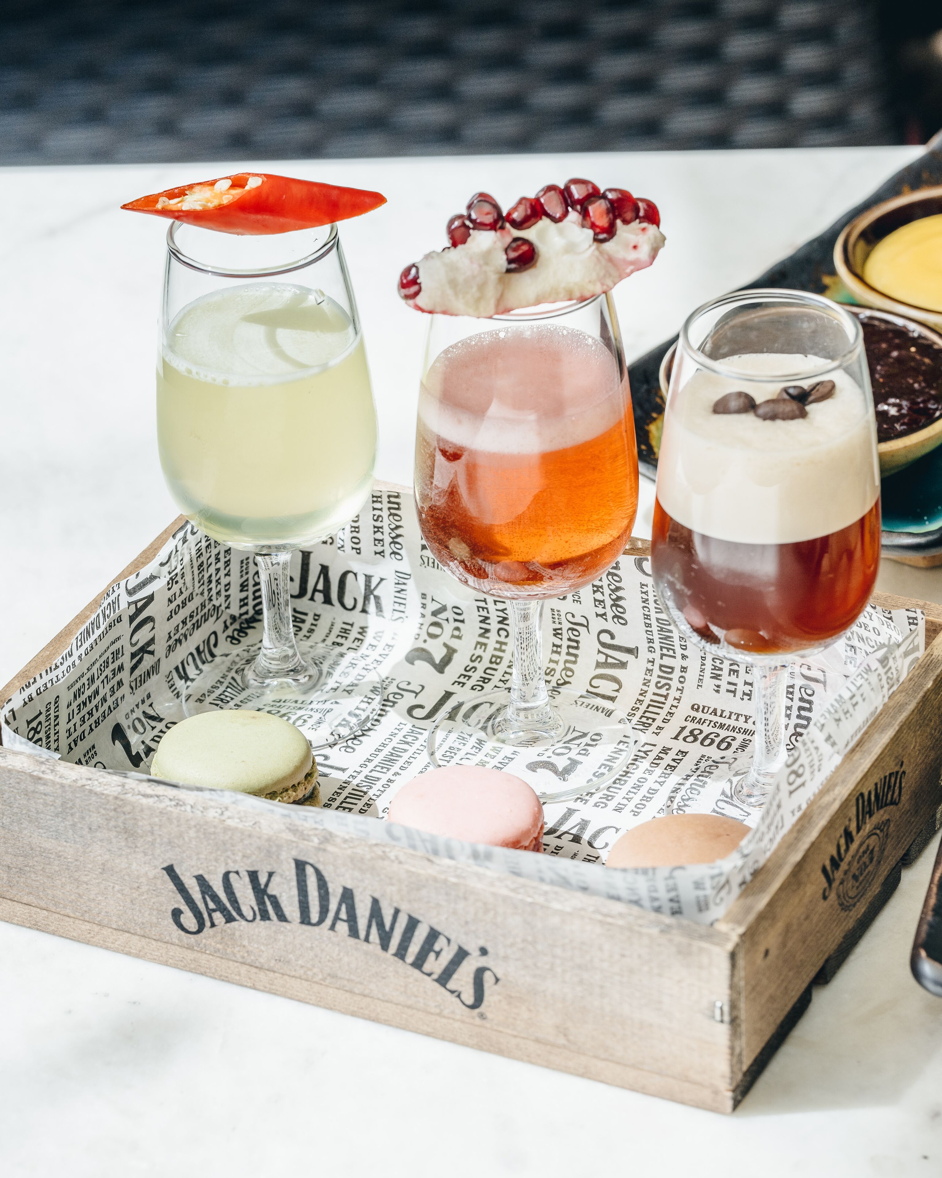 A tray with three glasses of beverages, two cookies, and a small bowl of chocolate.