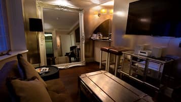 A cozy living room with a large mirror, a leather sofa, a coffee table, and a TV mounted on the wall.