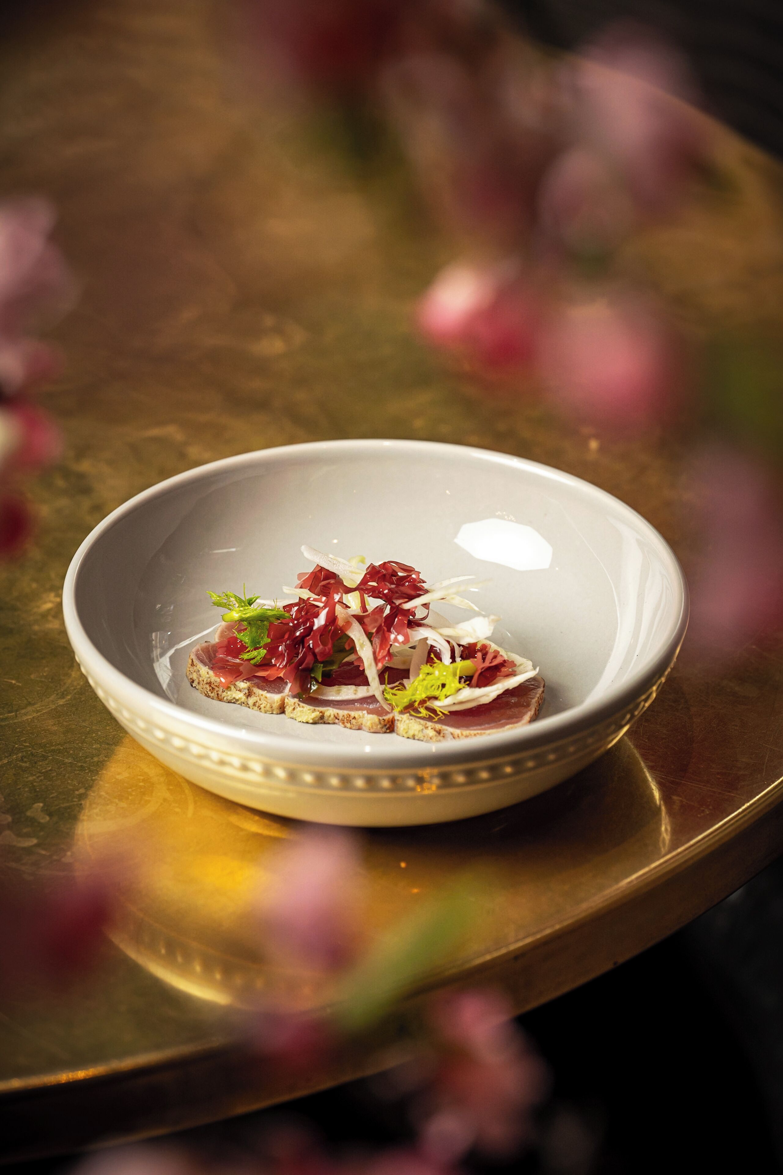 A white bowl with a dish on a reflective surface.