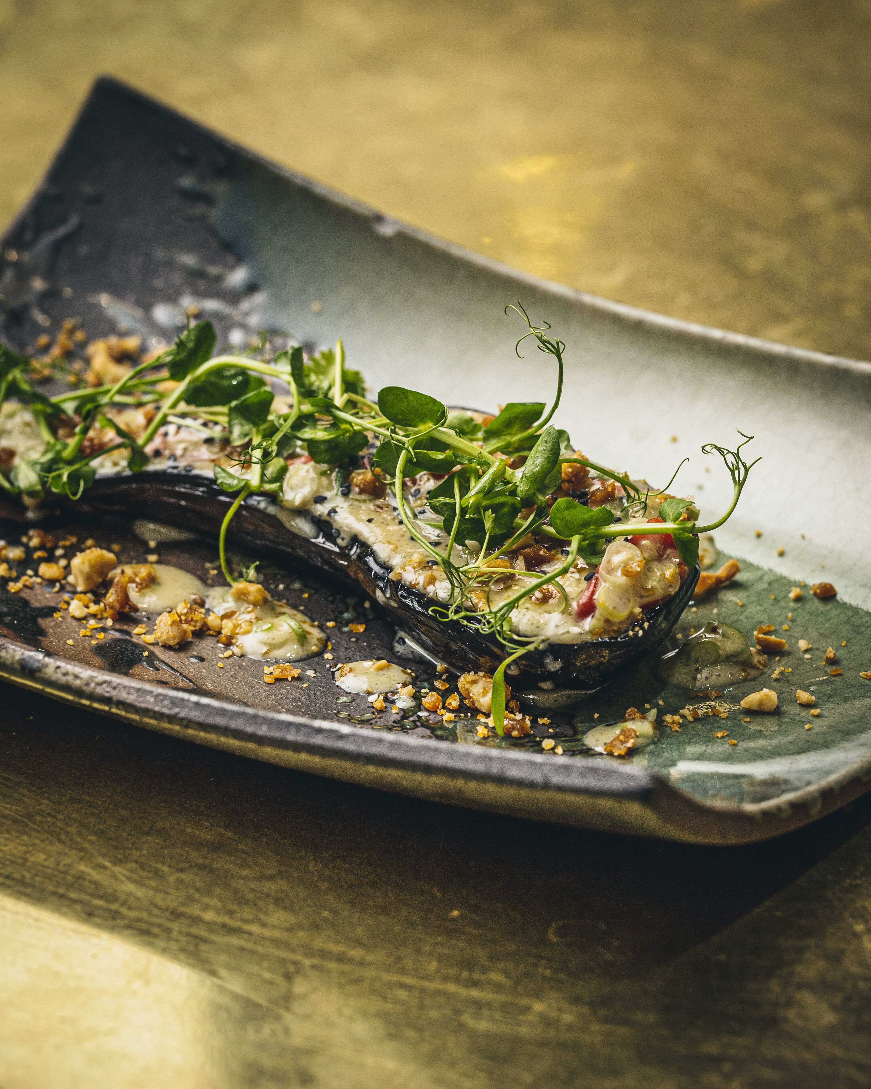 A dish with greens, nuts, and a dark sauce on a plate.