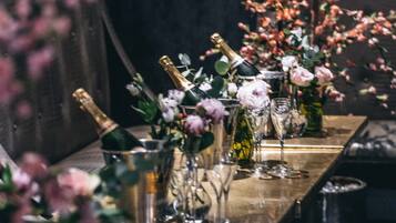 A long table with champagne bottles and glasses, surrounded by floral arrangements.