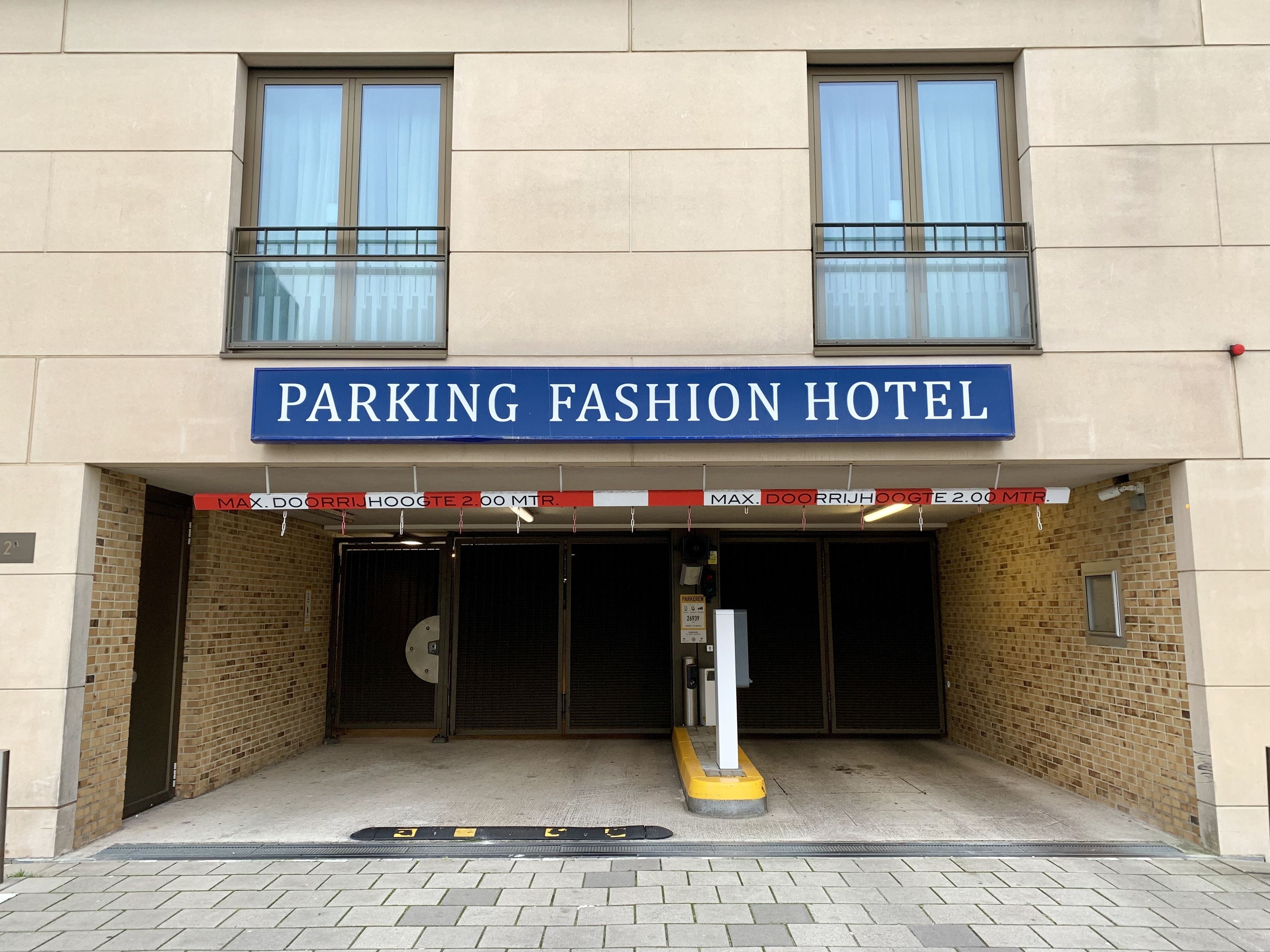 Um edifício com uma placa que diz "PARKING FASHION HOTEL" e uma taxa máxima de estacionamento de 2,00 MTR.