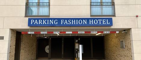 Um edifício com uma placa que diz "PARKING FASHION HOTEL" e uma taxa máxima de estacionamento de 2,00 MTR.