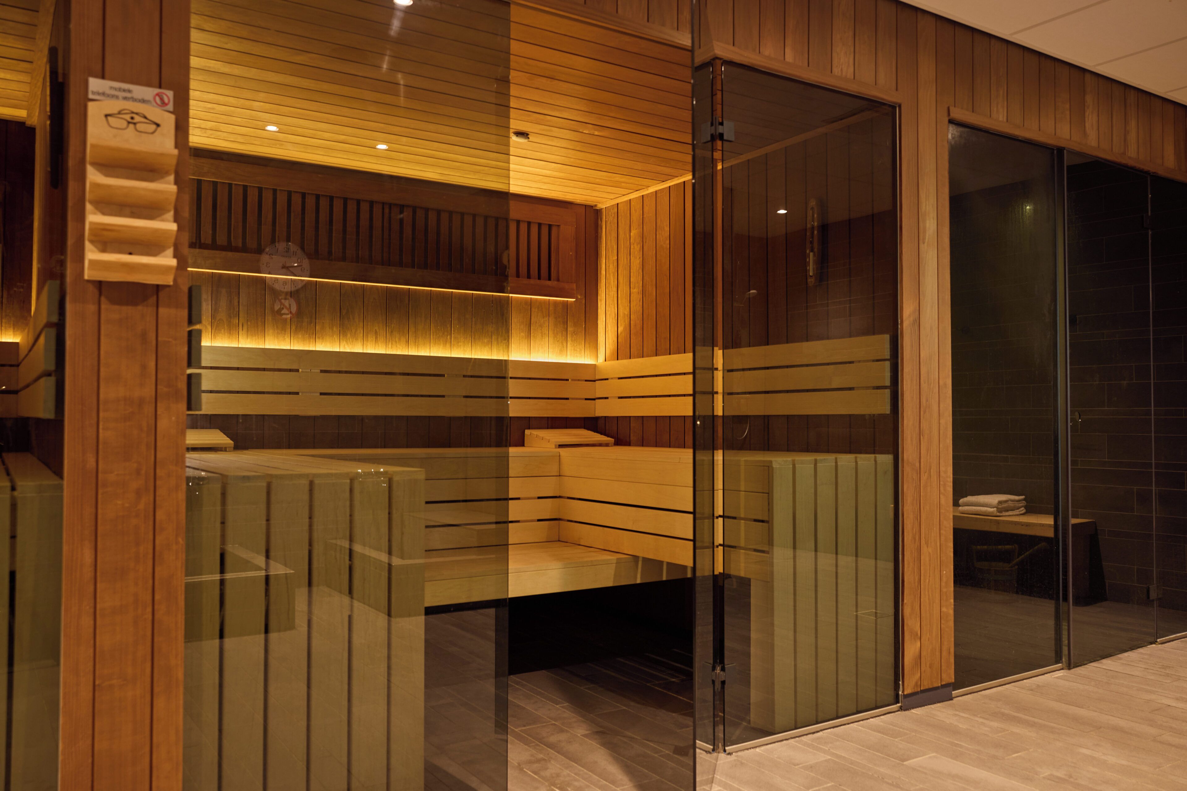 A sauna room with wooden benches and a glass partition.