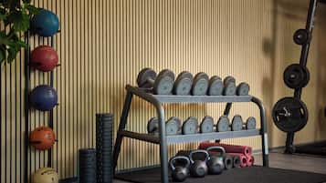 Een sportschool met een rek dumbbells, medicine ballen en kettlebells.