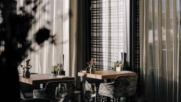 Un comedor con una mesa y sillas, una ventana con persianas y una planta decorativa.
