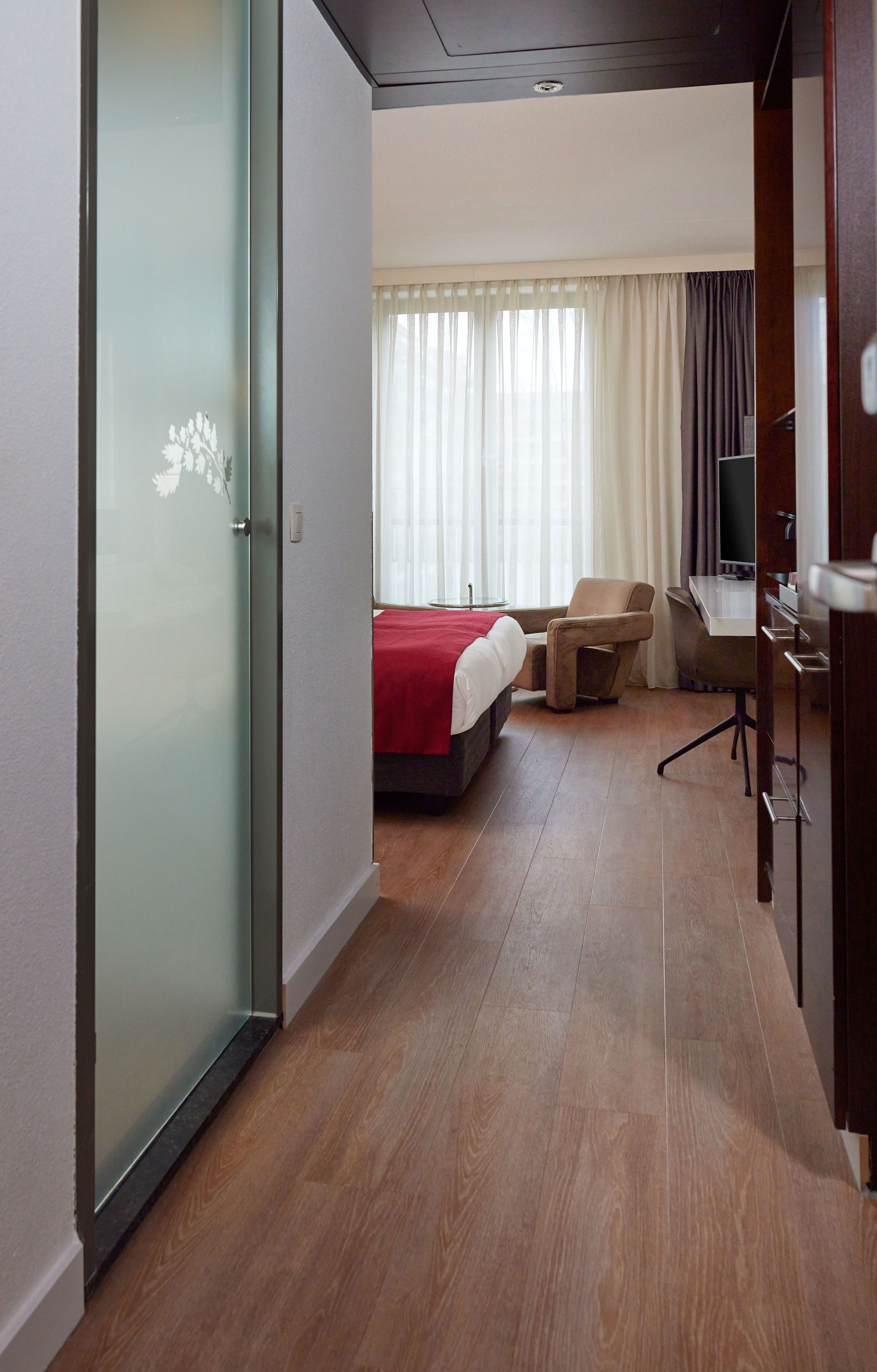 Ein Hotelzimmer mit Bett, Schreibtisch, Stuhl und Fernseher.