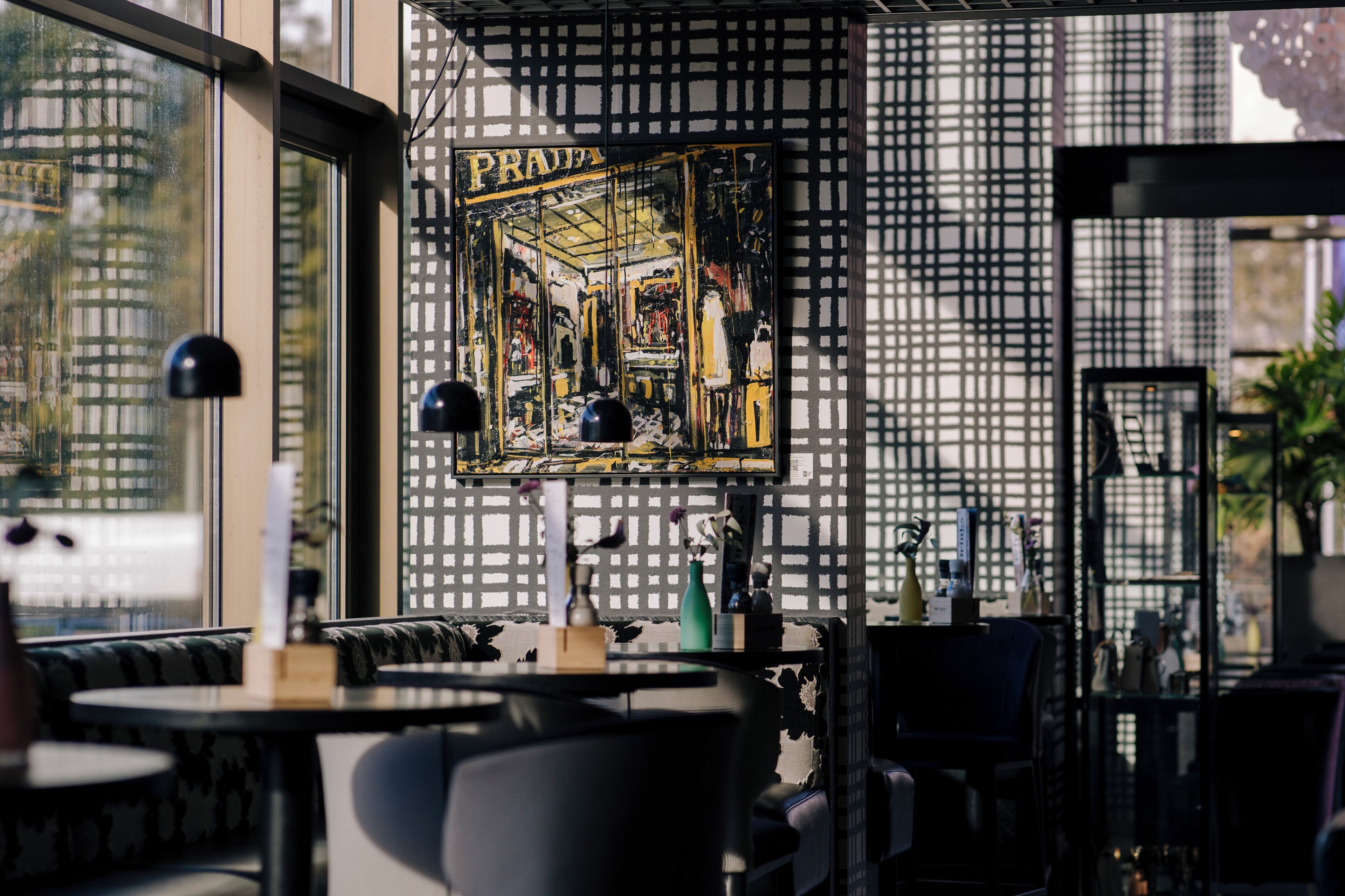 A restaurant interior with a patterned wall, a framed artwork, and a window view.