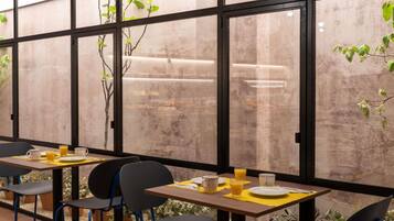 A dining area with tables set for breakfast, featuring yellow placemats and white plates.