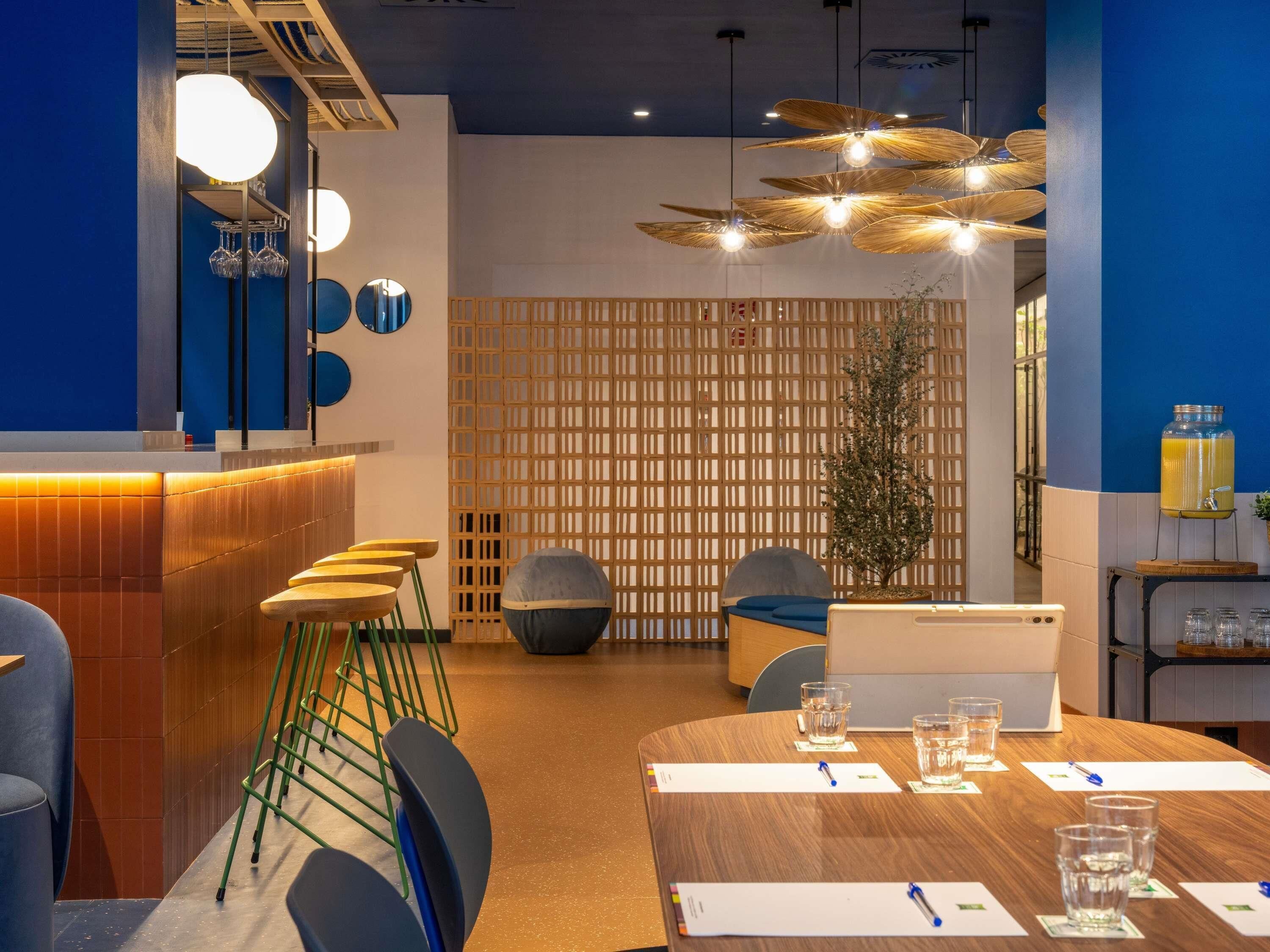 Una sala de conferencias moderna con una mesa de madera, sillas, un ordenador portátil y una planta decorativa.