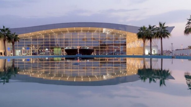 A modern hotel with a large glass facade, palm trees, and a pool reflecting the building. - Holiday Inn Riyadh Izdihar by IHG (Riyadh)