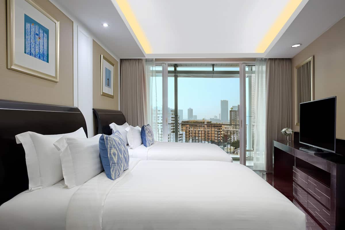 A hotel room with two beds, a TV, and a large window with a city view.