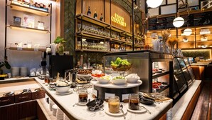 A buffet setup with various food items and condiments, a bar area with shelves of bottles, and a sign reading "DUSIT GOURMET".