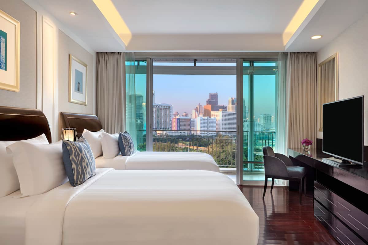 A hotel room with two beds, a TV, and a desk.