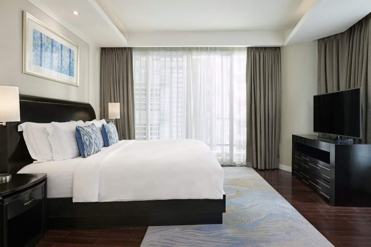 A hotel room with a large bed, a TV, and a view of the city through the window.