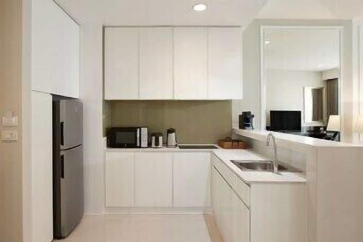 A modern kitchen with white cabinets, a microwave, a coffee maker, and a sink.