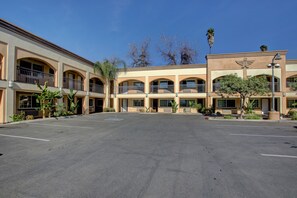 A multi-story hotel with a central courtyard, balconies, and palm trees.