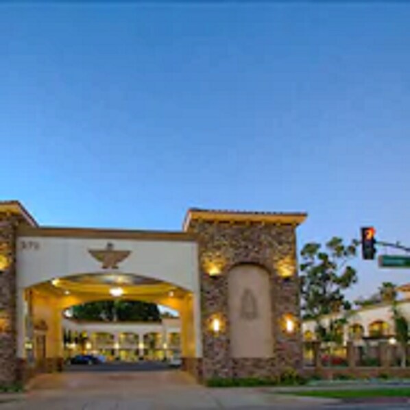 A hotel entrance with a stone facade, a large archway, and a sign above the entrance.
