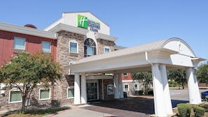A Holiday Inn Express & Suites building with a stone facade, a covered entrance, and a clear blue sky. - Holiday Inn Express & Suites Dallas Southwest-Cedar Hill by IHG (Cedar Hill)