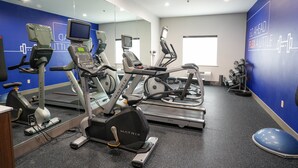 Une salle de sport équipée de machines de cardio, de miroirs et décorée de motifs inspirants sur les murs.