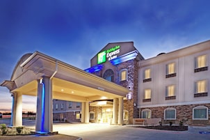 Un Holiday Inn Express & Suites con un espacio exterior cubierto y fachada de piedra.