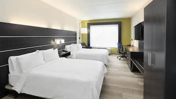 Een hotelkamer met twee bedden, een bureau, een stoel, een televisie en een kledingkast.