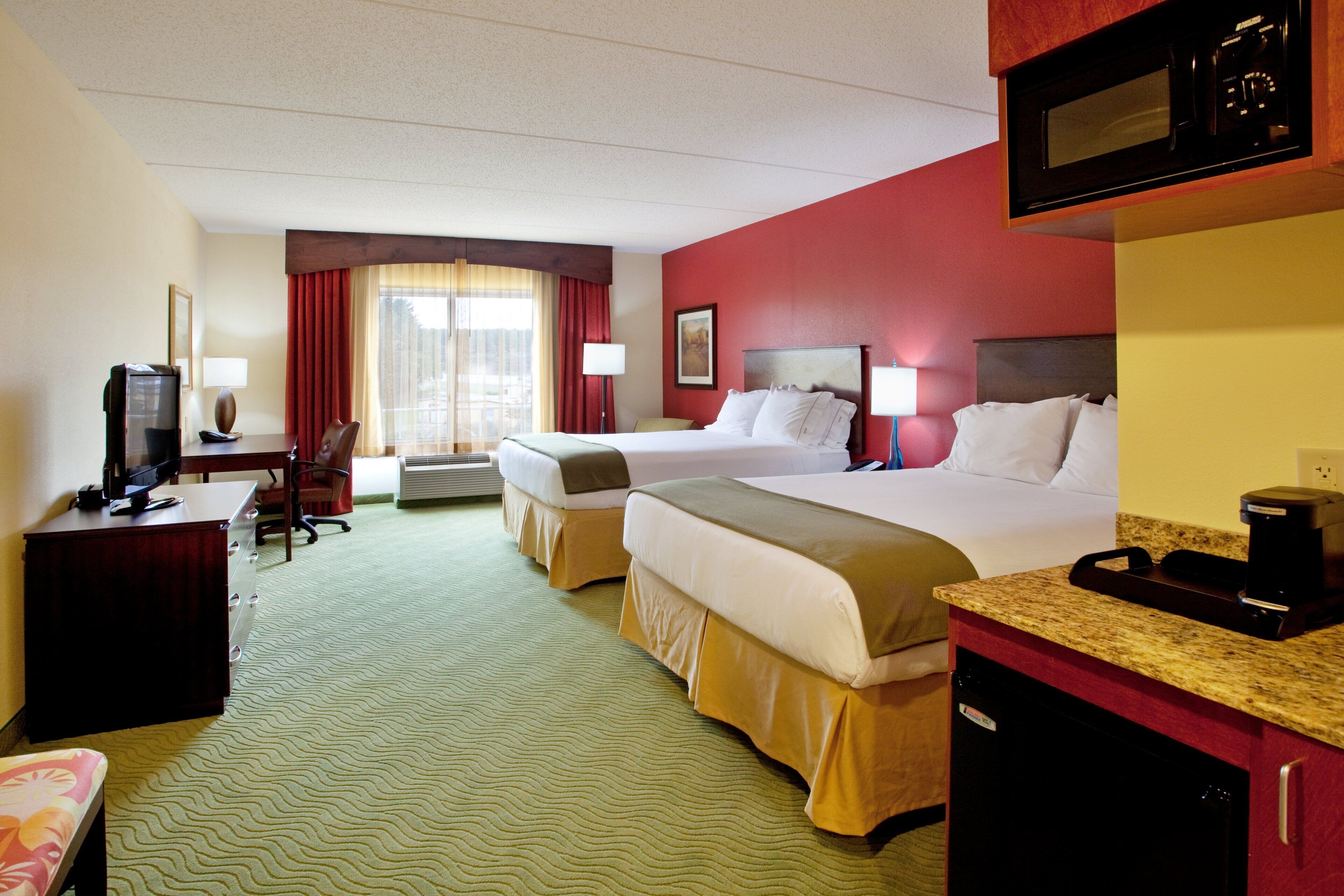 A hotel room with two beds, a desk with a computer, a television, and a microwave.