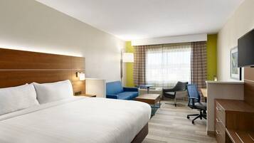 A hotel room with a large bed, a desk, a chair, a television, and a window with curtains.