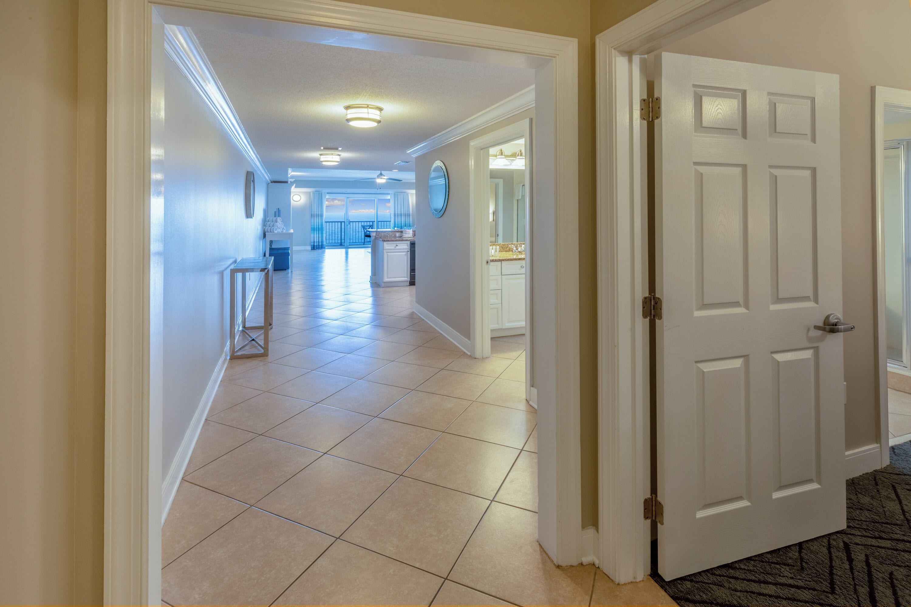 A hallway with a tiled floor leading to a kitchen area.