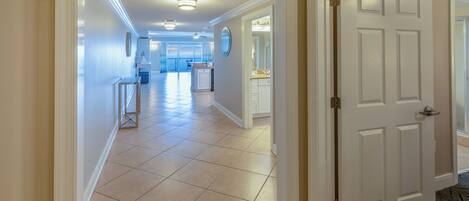 A hallway with a tiled floor leading to a kitchen area.