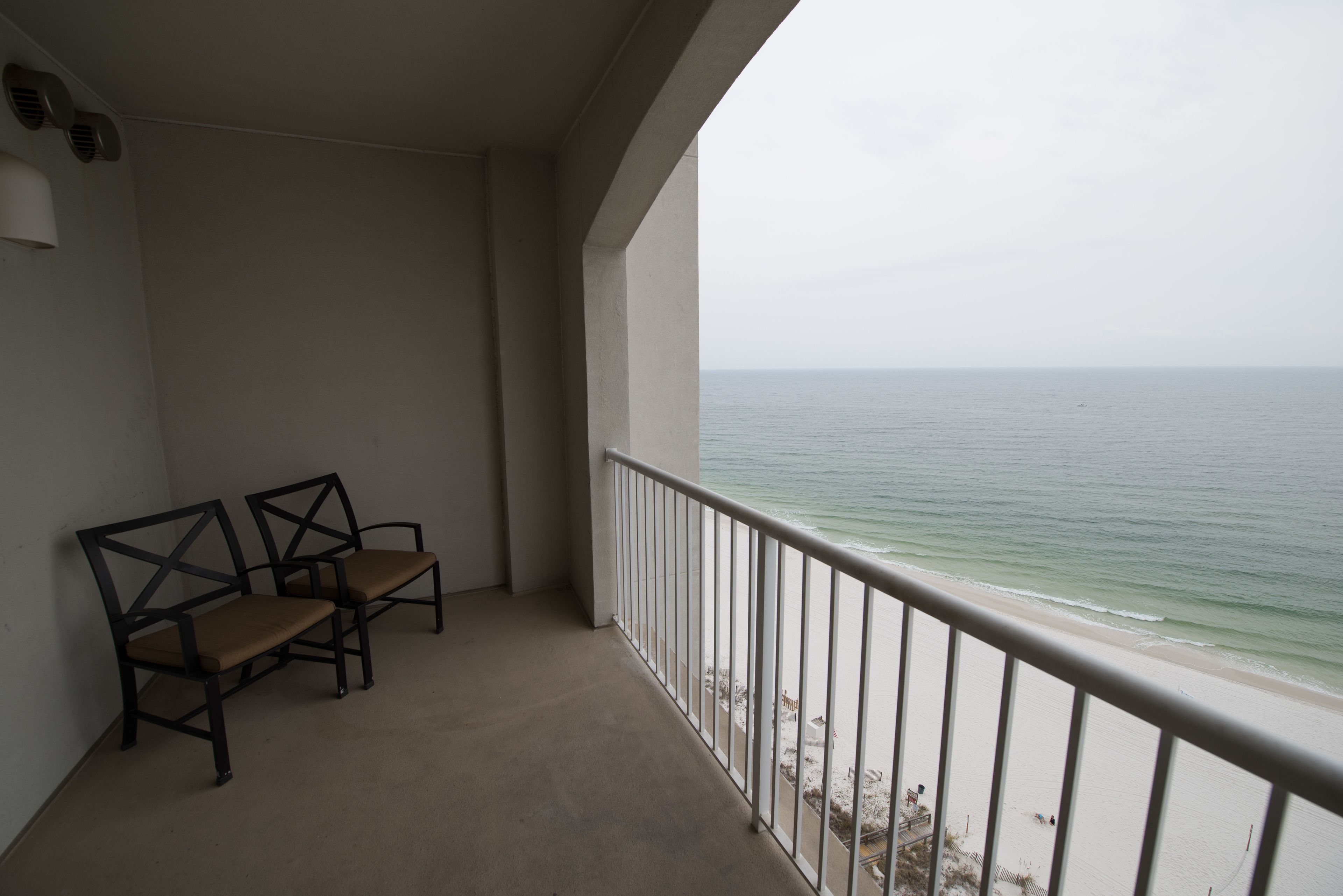 A balcony with two chairs and a view of the ocean.