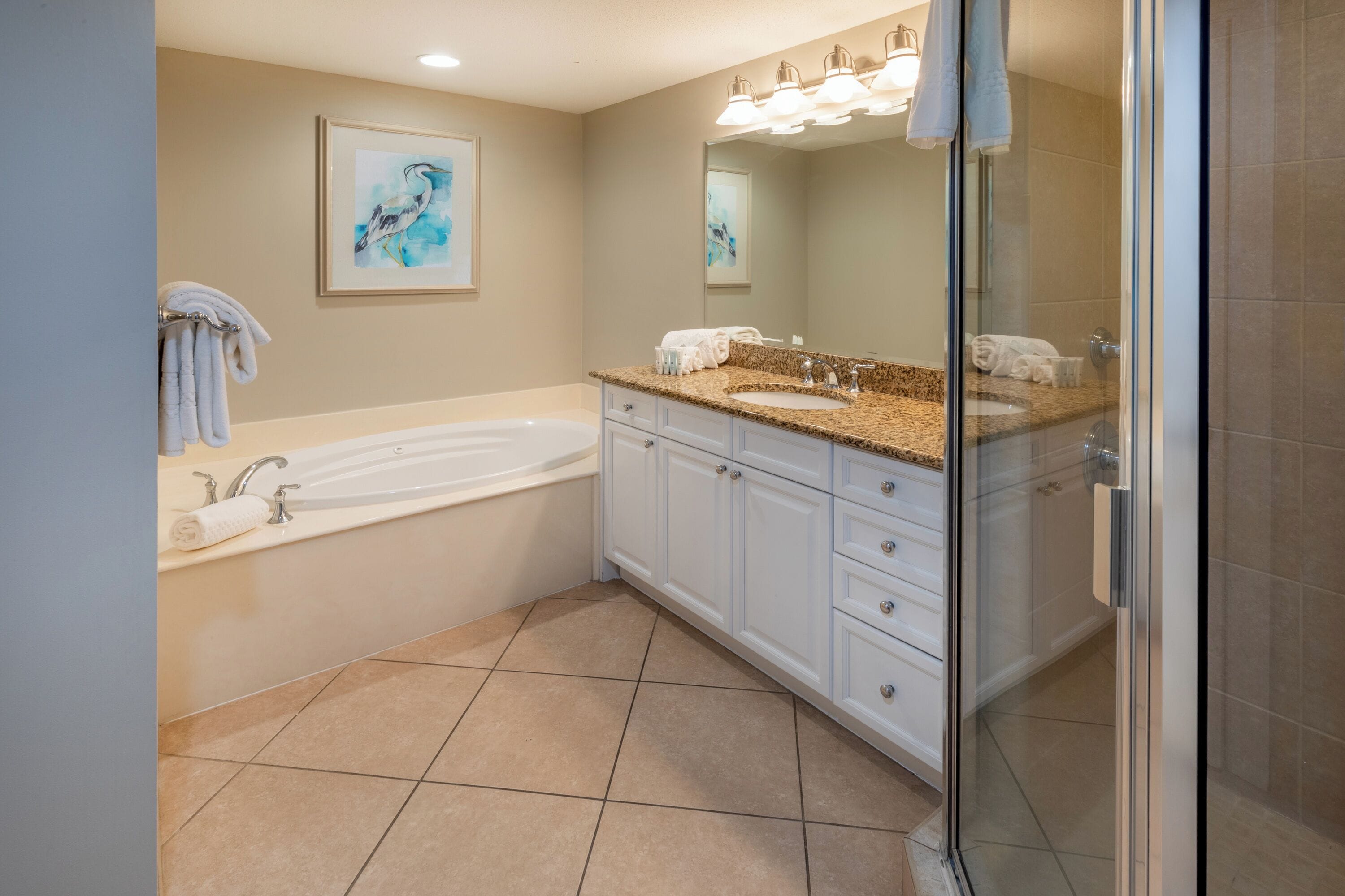 A modern bathroom with a bathtub, a large vanity with a sink, and a glass shower enclosure.