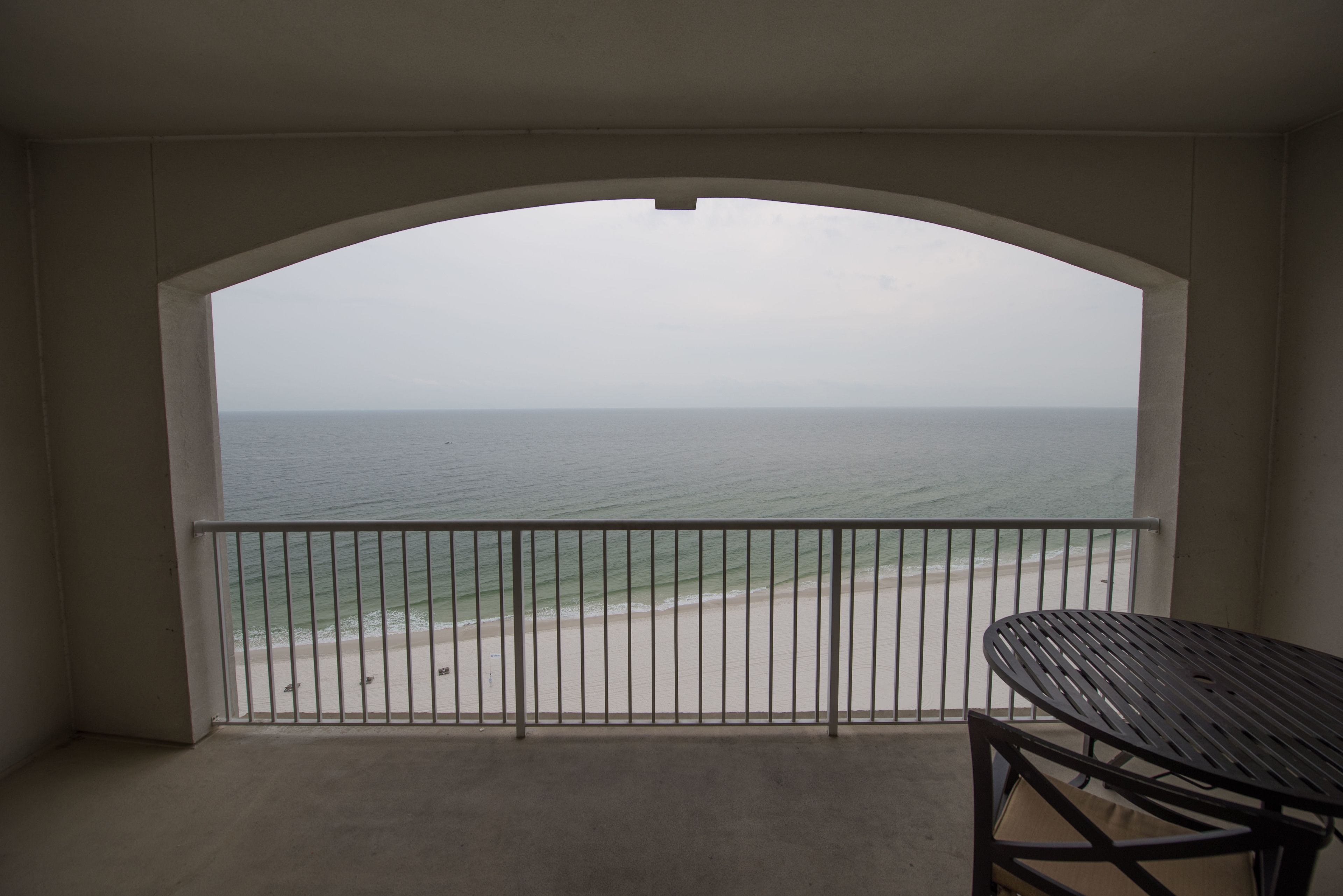 A balcony with a view of the beach and ocean.