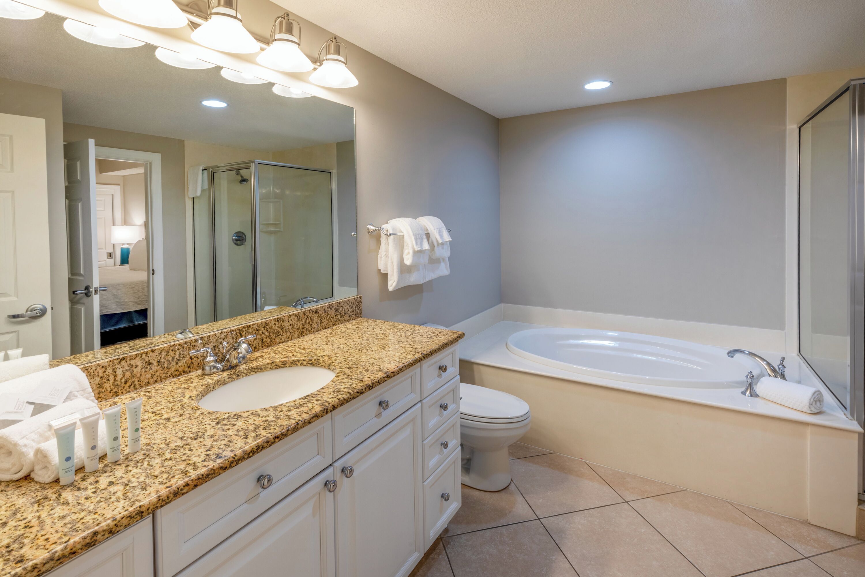 Une salle de bain moderne avec un lavabo sur un plan de travail en granit, une baignoire sur pieds et une douche à parois de verre.