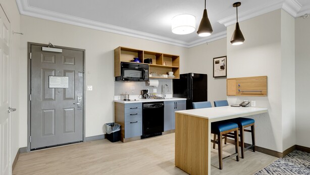 A compact kitchen with a microwave, refrigerator, and a small dining area with blue chairs. - Candlewood Suites San Antonio Downtown by IHG (San Antonio)