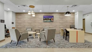 A modern reception area with a wooden wall, a flat-screen TV, and a desk with a computer. - Candlewood Suites San Antonio Downtown by IHG (San Antonio)