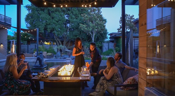 Un área de patio al aire libre con una chimenea, asientos y una mesa de comedor.