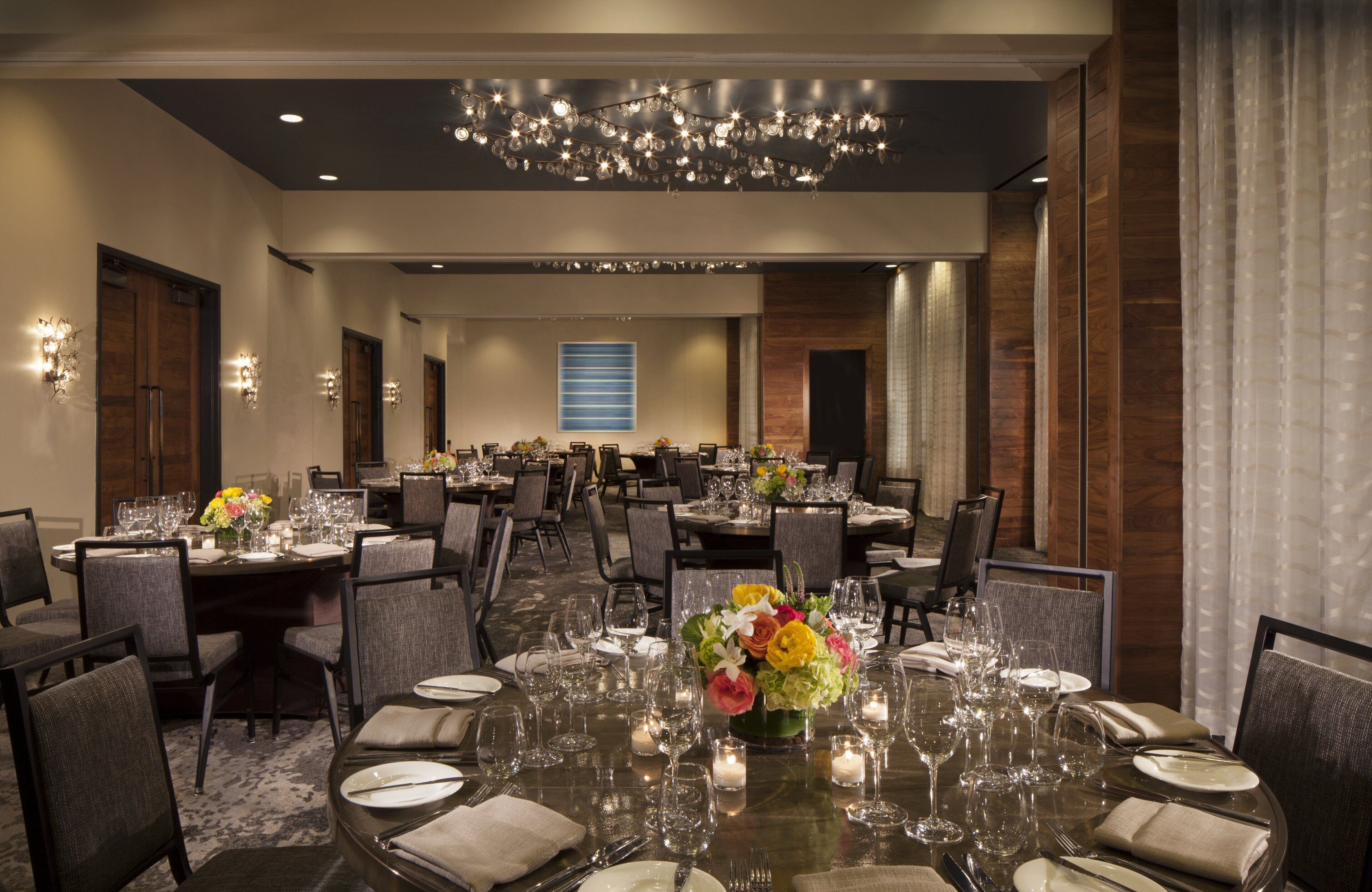 A spacious banquet hall with multiple round tables set for dining, featuring clear glassware and centerpieces.