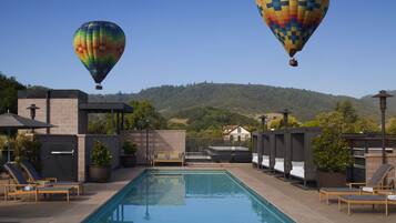 A swimming pool with lounge chairs and a hot air balloon in the background.