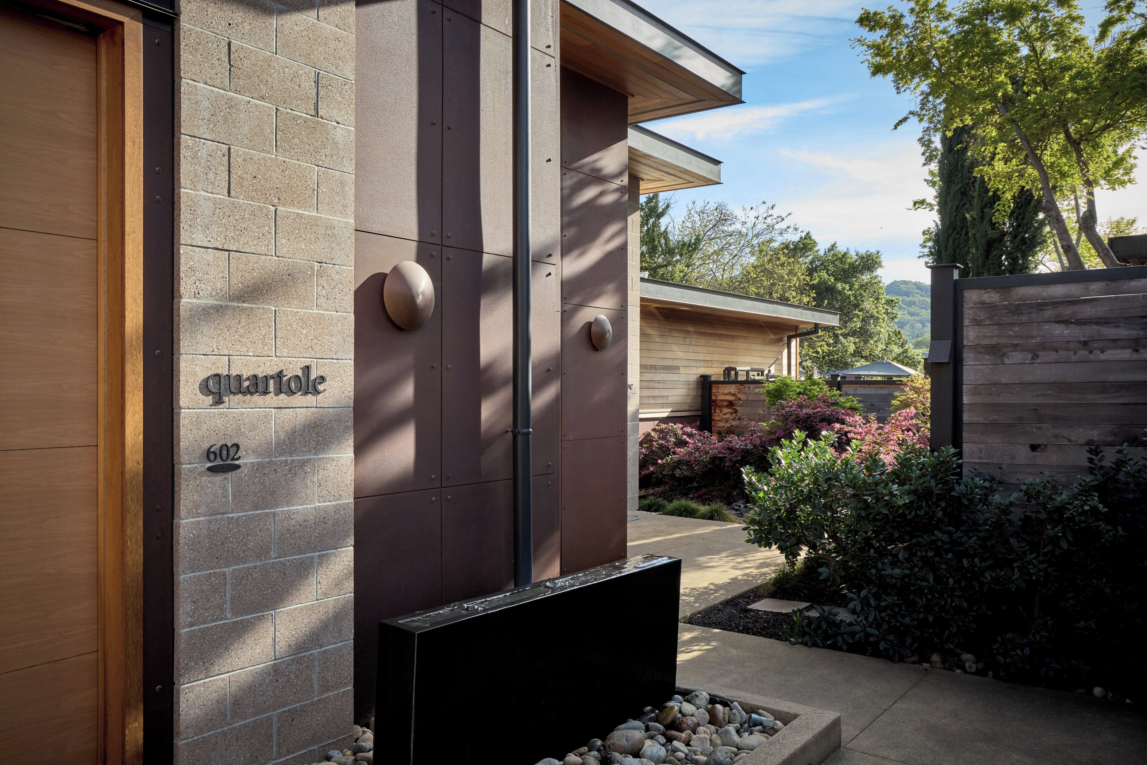 A modern building with a stone facade, a wooden door, and a number "602" on the wall.