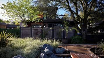Una casa moderna con terraza de madera, un sendero de piedra y un pequeño estanque.