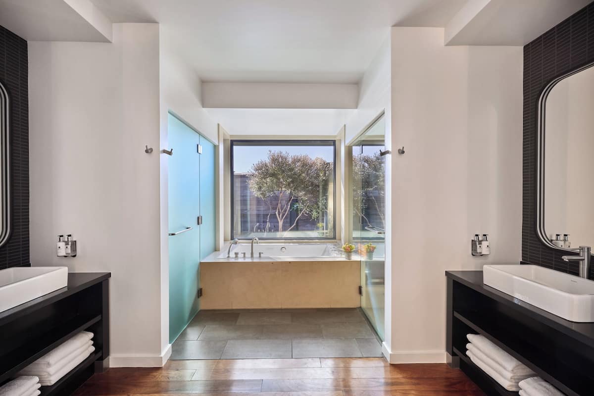 Un baño moderno con un ventanal amplio, dos lavamanos y una ducha a ras de suelo.