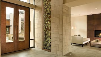 A modern interior with a stone wall, a vertical garden, a sofa, and a fireplace.