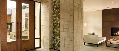 A modern interior with a stone wall, a vertical garden, a sofa, and a fireplace.